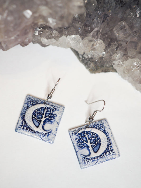 Hand-made, blue and white, square dangle earrings with a large crescent moon and forest scene