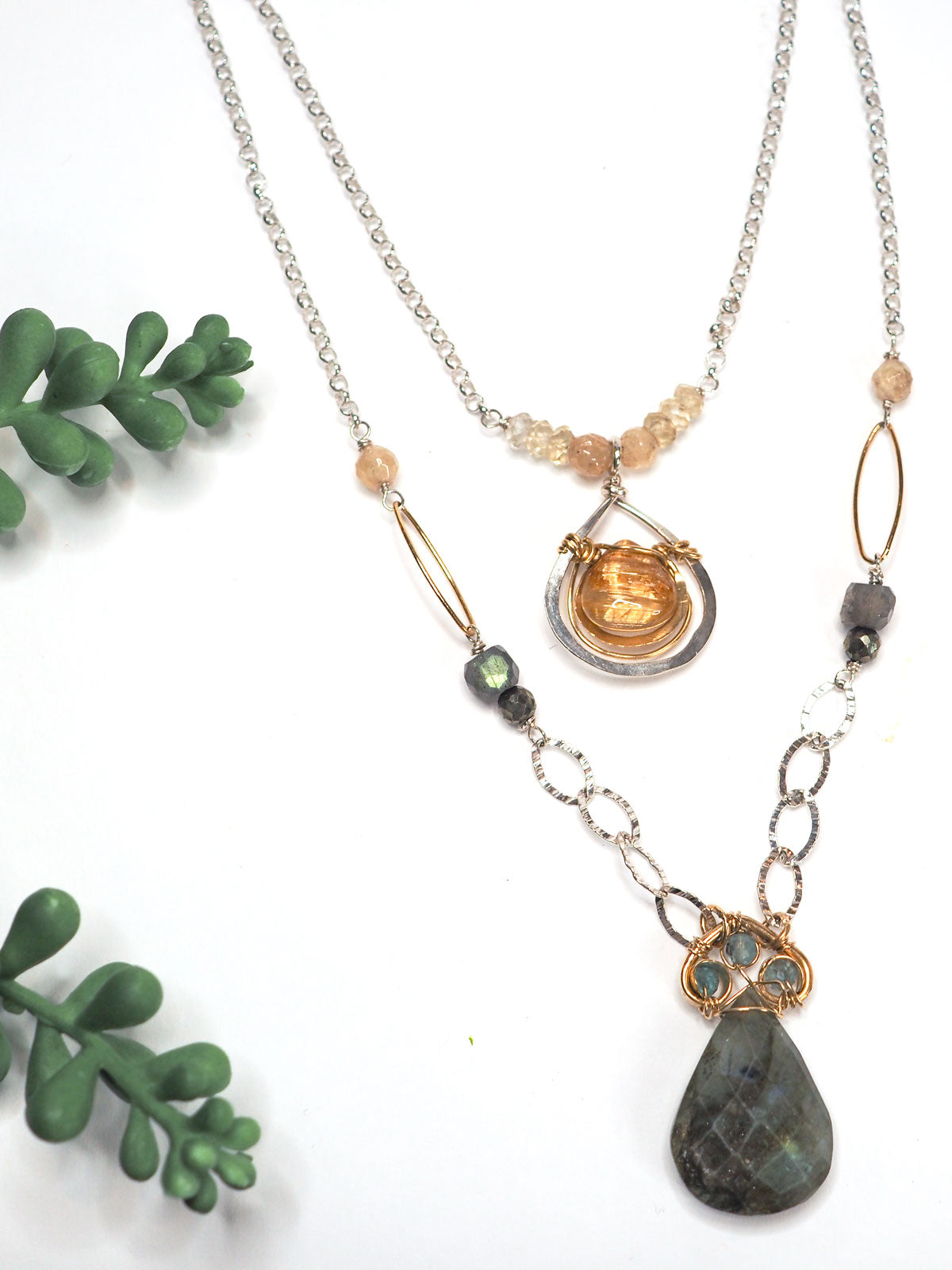 This beautifully layered statement necklace features a faceted gold rutilated quartz bezel framed in hammered 14K gold filled and sterling silver as well as a pear-shaped labradorite drop crowned with three apatite gems, linked together in brass into the shape of a spade.
