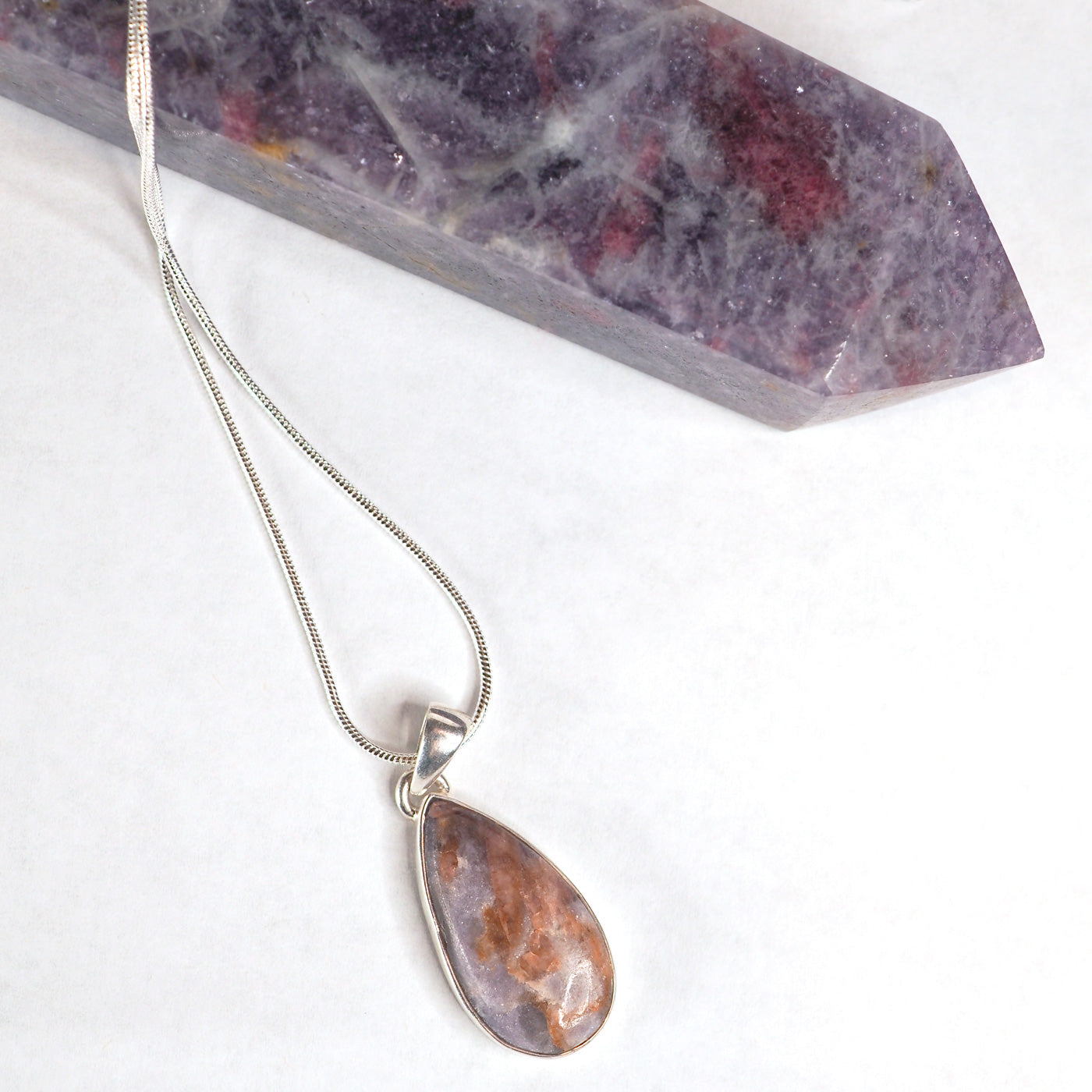 Pear-shaped Unicorn Stone Pendant shown on a silver chain with a Unicorn Stone tower