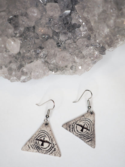 Hand-made triangular ceramic dangle earrings featuring a flying bird silhouetted against a stylized moon 