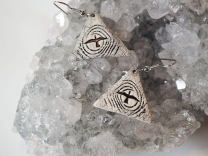 Hand-made triangular ceramic dangle earrings featuring a flying bird silhouetted against a stylized moon  - shown on a gray amethyst druzy