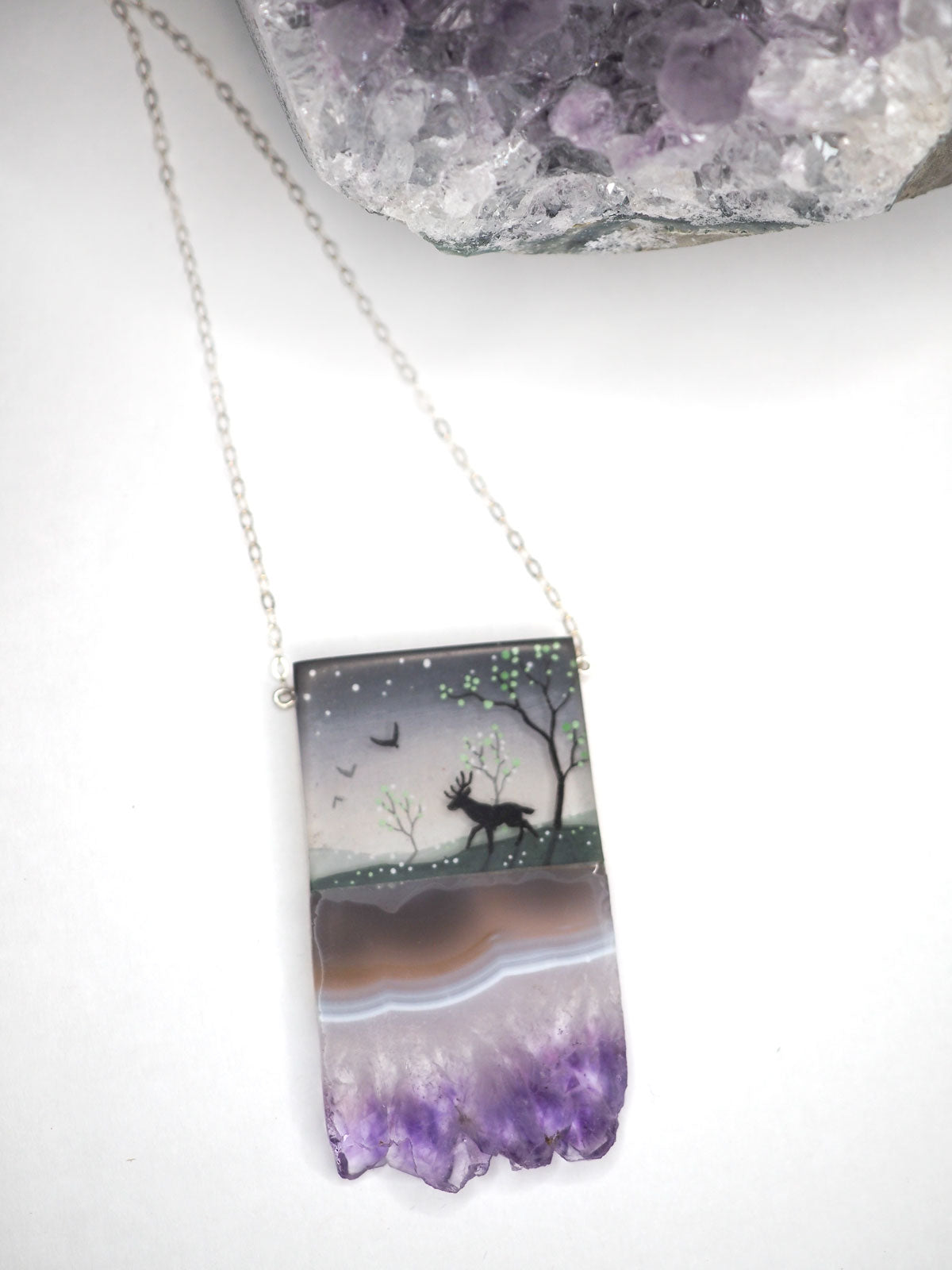 Hand-painted resin and amethyst slice necklace on a silver chain with a bird and deer in a forest scene