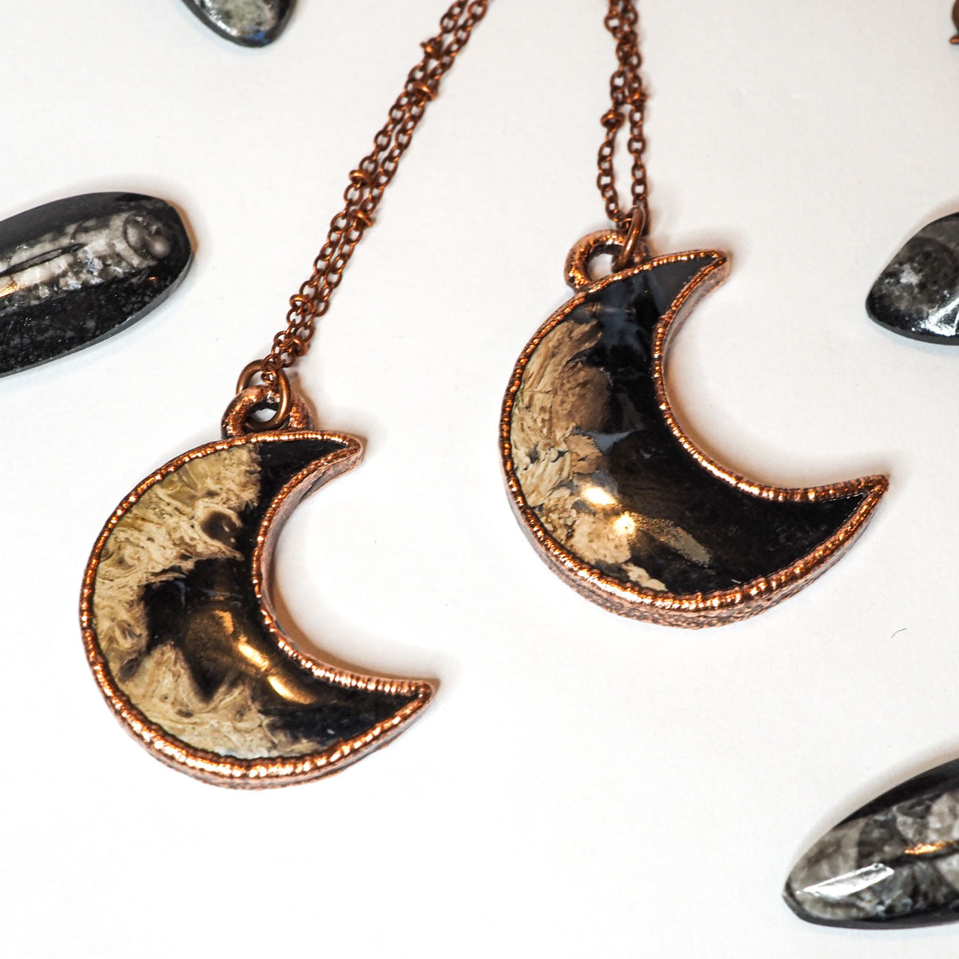 2 moon-shaped copper electroformed pendants featuring petrified palm wood on copper chains