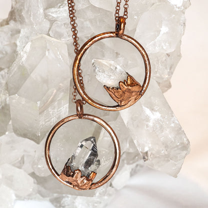2 copper chain necklaces with a clear quartz crystal point inside a round copper circle