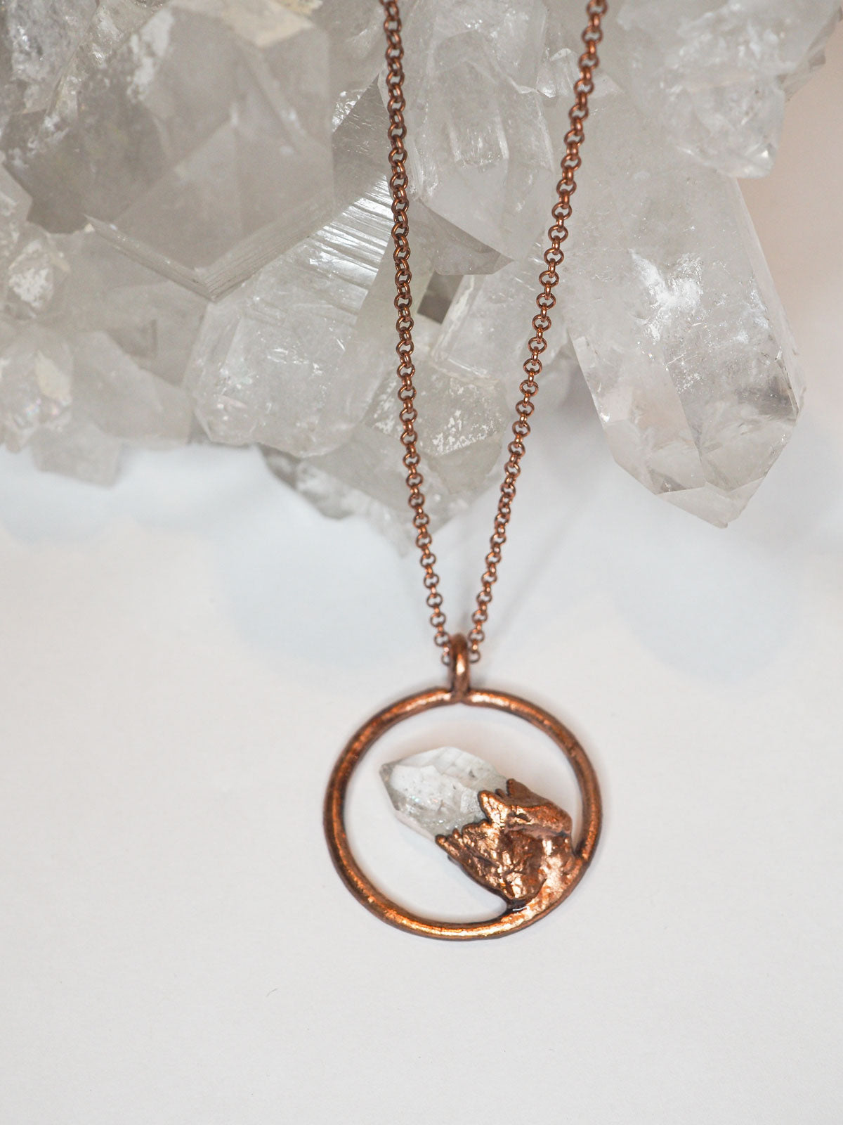 Copper chain necklace with a clear quartz crystal point inside a round copper circle