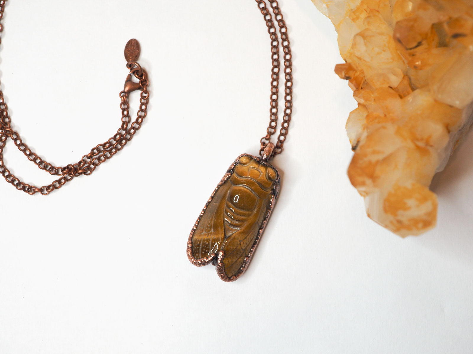 Carved tiger's eye cicada electroformed copper pendant up close shot on a copper chain