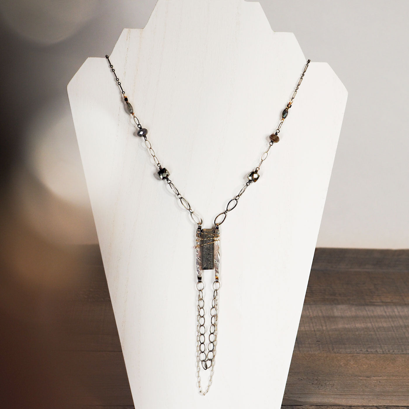 A flock of birds flies around a sparkly black sunstone brick at the center of this statement necklace. Pyrite cushion cut cubes and Labradorite faceted gemstones sprinkle the long wide link sterling silver chain.