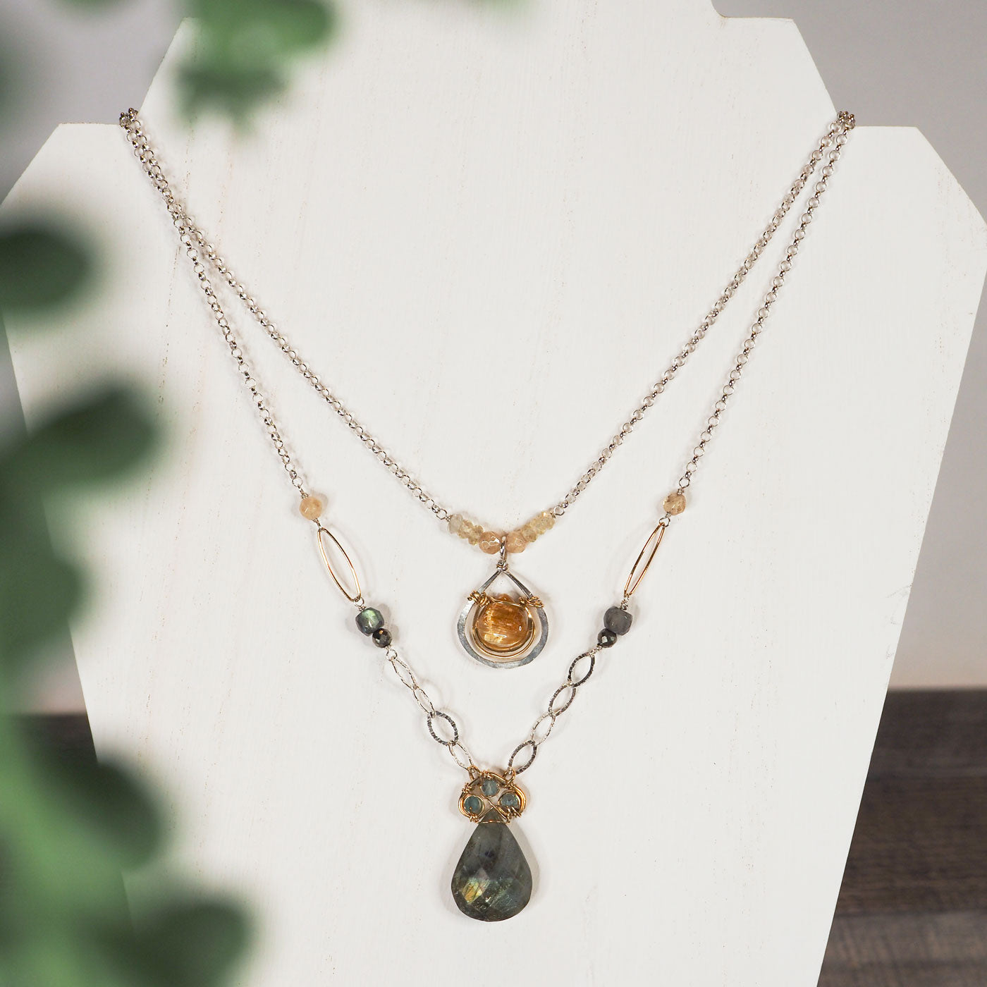 This beautifully layered statement necklace features a faceted gold rutilated quartz bezel framed in hammered 14K gold filled and sterling silver as well as a pear-shaped labradorite drop crowned with three apatite gems, linked together in brass into the shape of a spade.