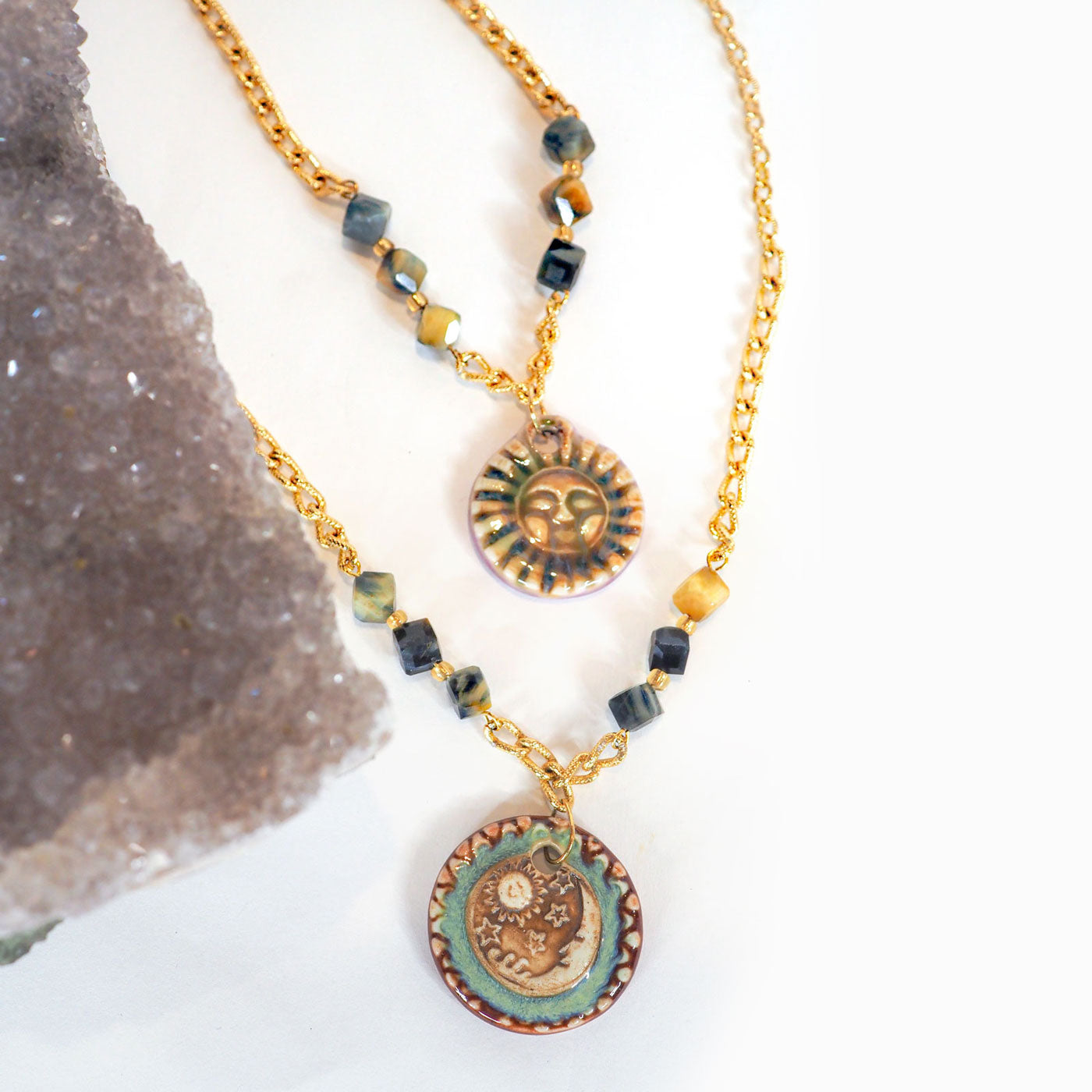 Hand-made ceramic sun and moon pendants hang between faceted blue Tiger's Eye beads on adjustable vintage gold chain necklaces.