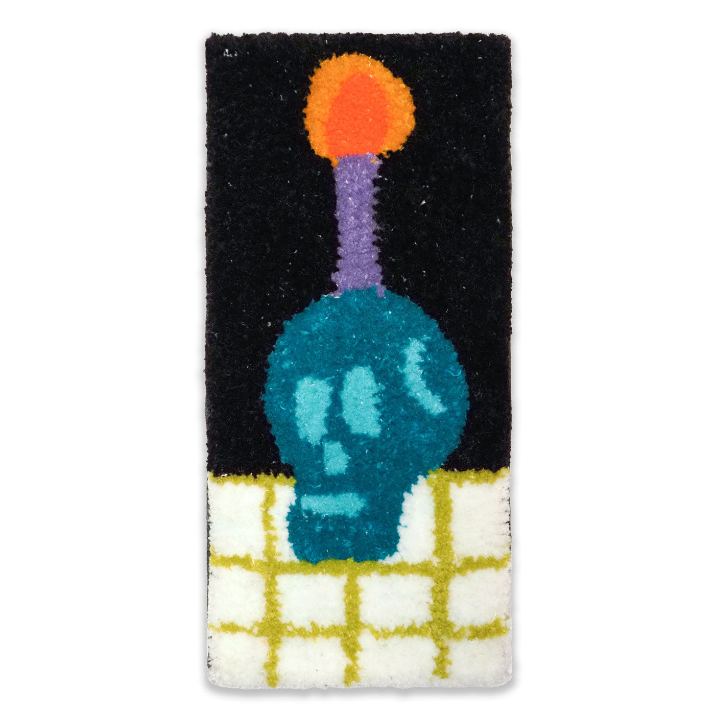 Hand-tufted wall hanging featuring a teal blue-colored skull on a white and green checked surface with a purple candle coming out of the top of its head