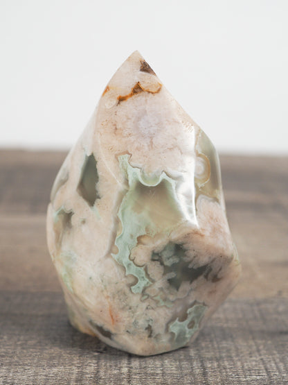 This sculpted flower agate flame with green inclusions is about 3" tall and 2" wide at its base.