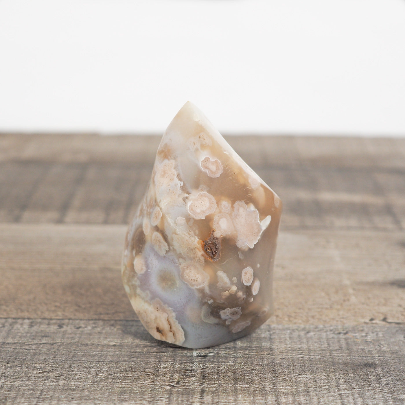 This sculpted flower agate flame with is about 2.5" tall and 1.5" wide at its base with beautiful blue agate inclusions.